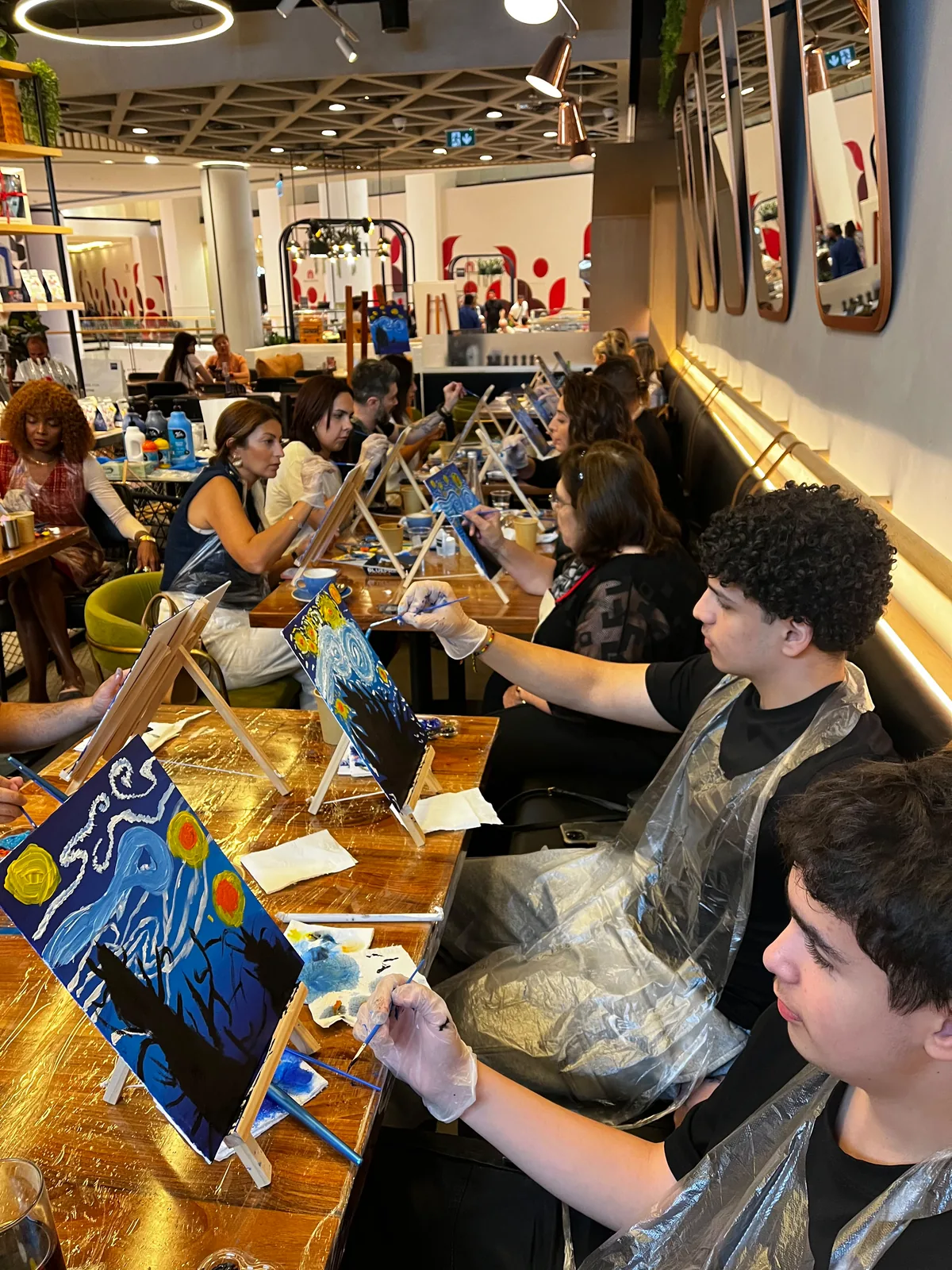 Guests painting Starry Night on tabletop easels at a CANVAS session