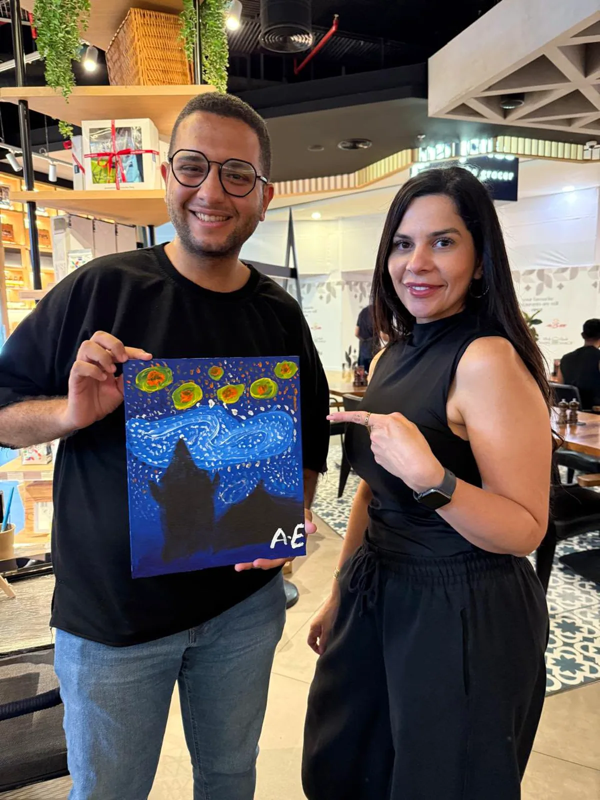 Two guests showing their completed Starry Night paintings