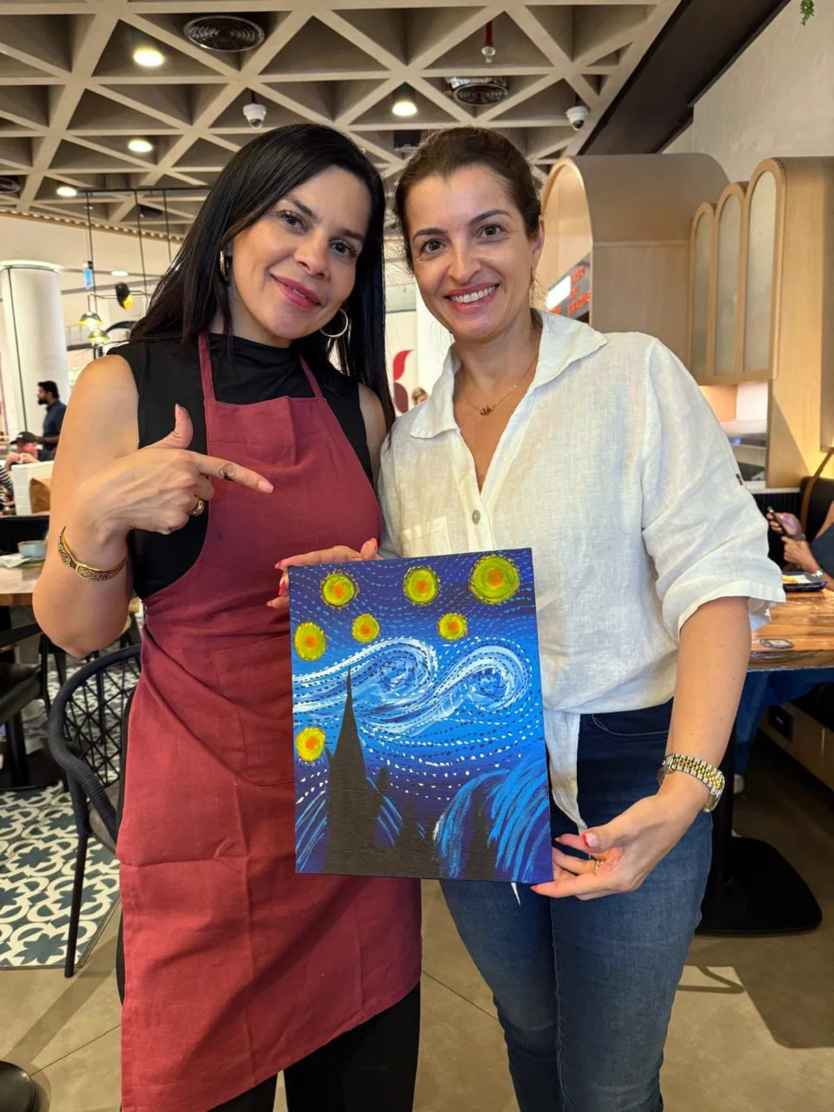 Two guests showing their completed Starry Night paintings
