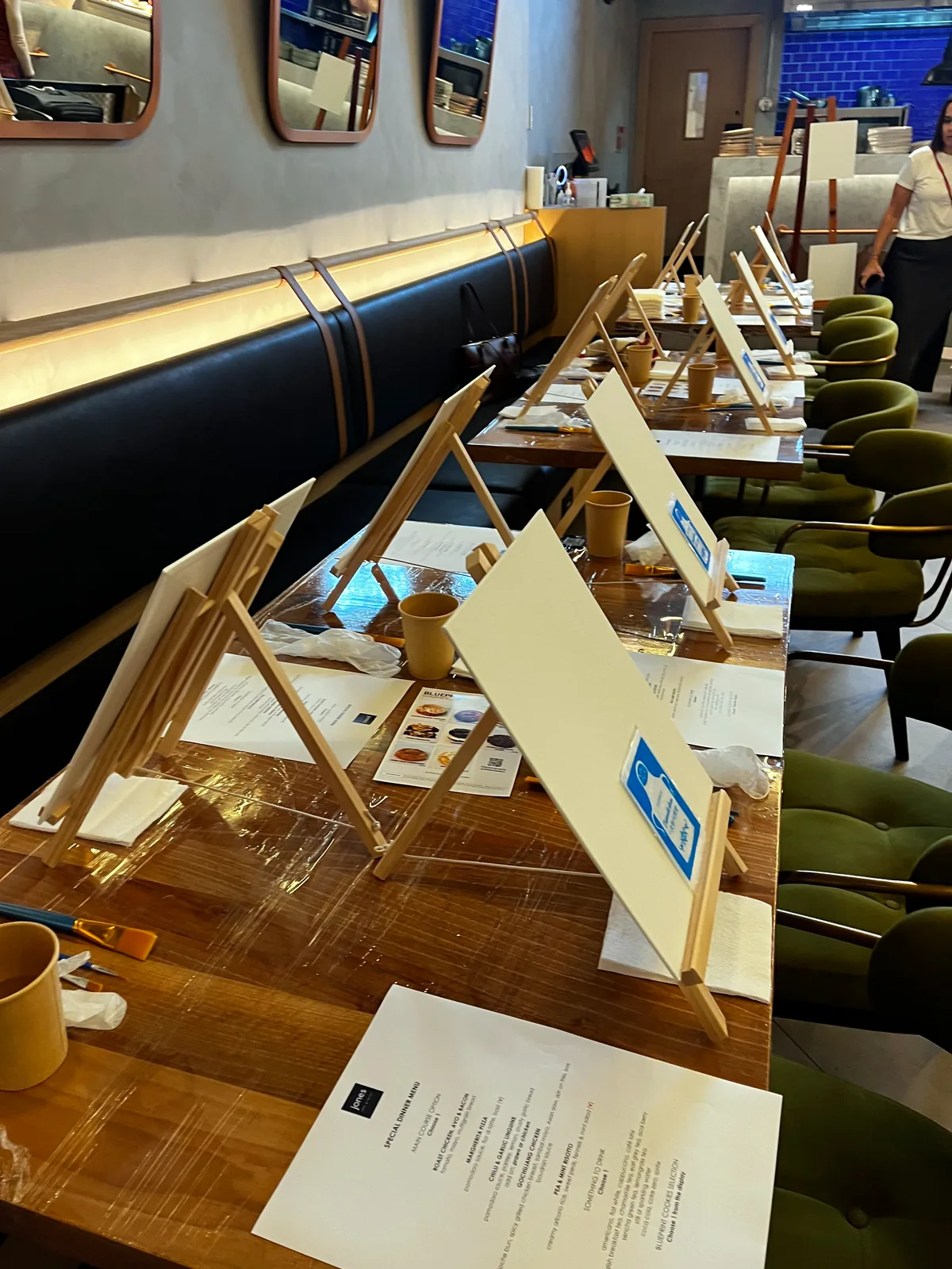 Easels and canvases set up on café tables before the session begins