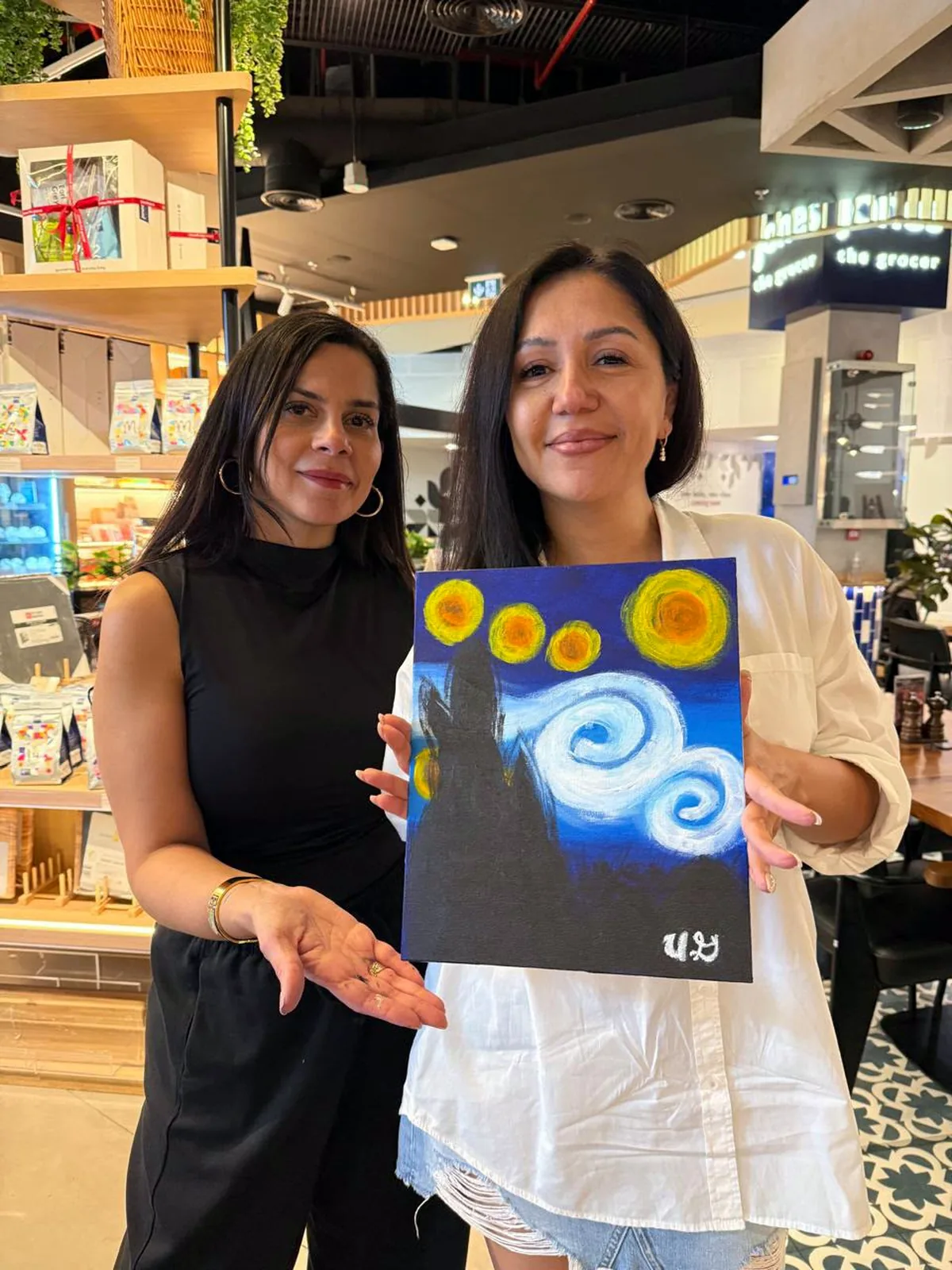 Two guests showing their completed Starry Night paintings
