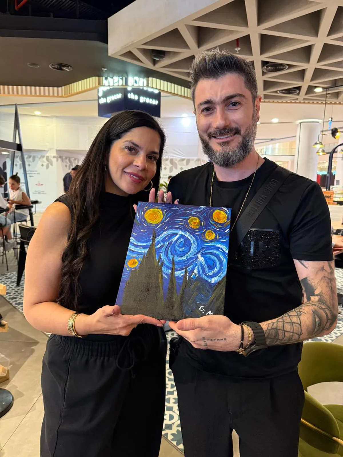 Two guests showing their completed Starry Night paintings