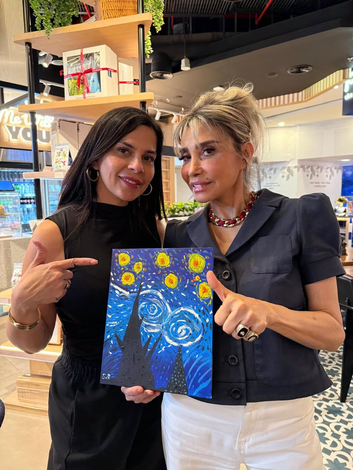 Two guests showing their completed Starry Night paintings