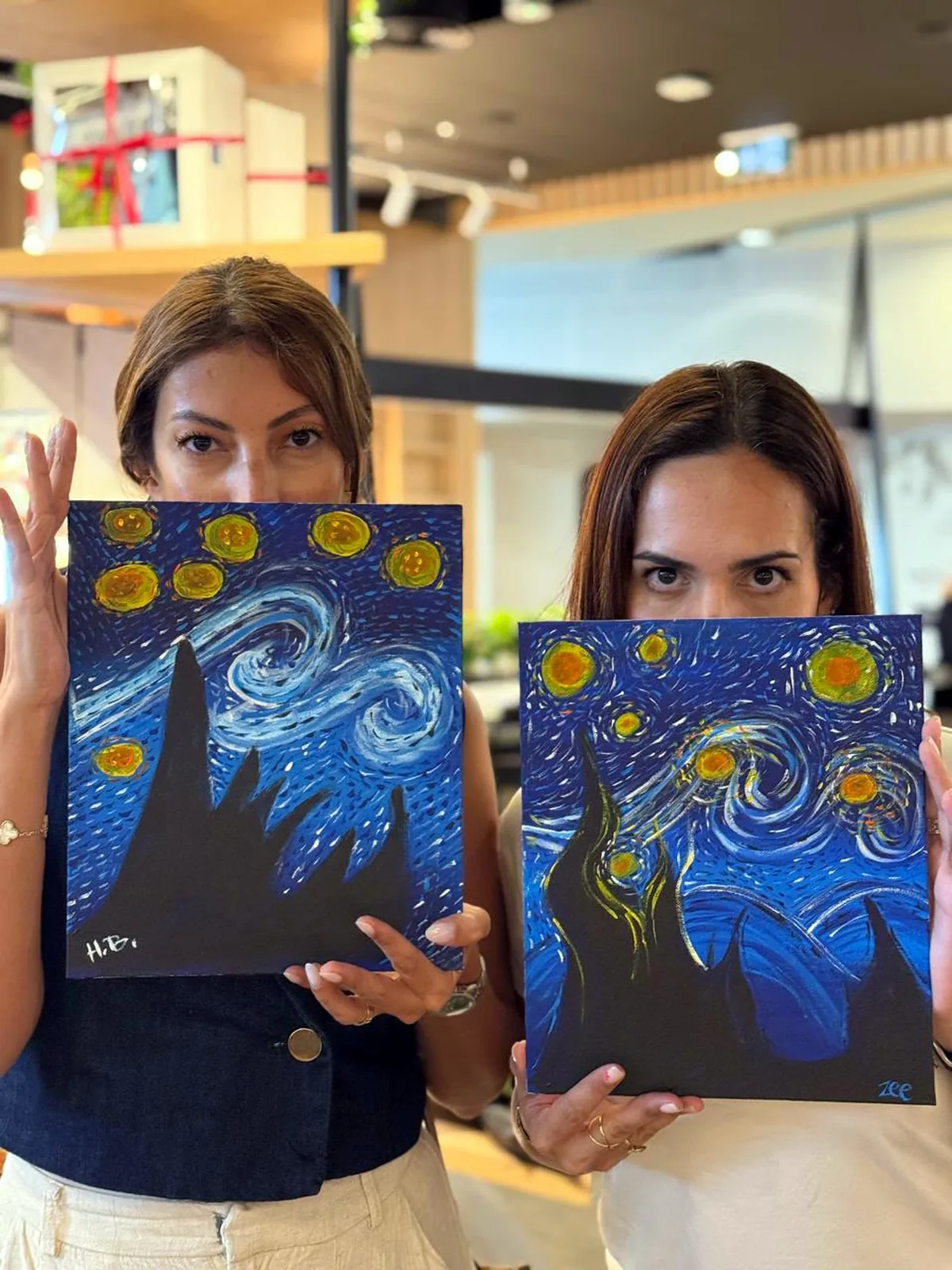 Two guests showing their completed Starry Night paintings